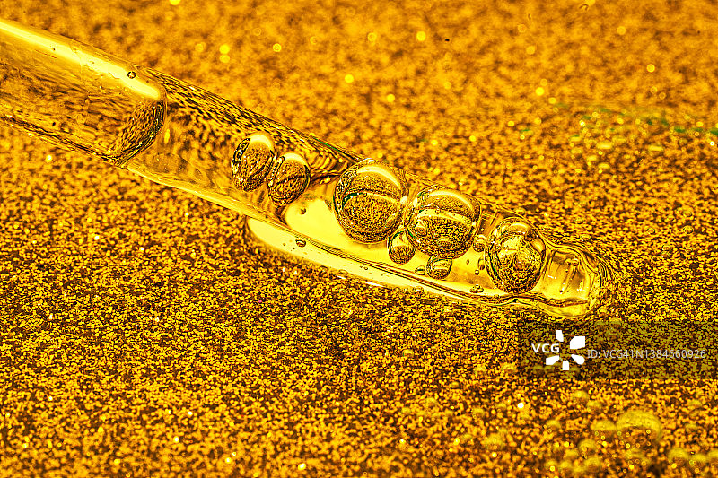 面部精华或精油与氧气气泡在金黄色背景上的滴管特写图片素材