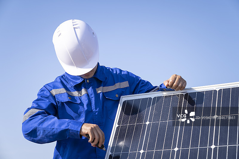 用太阳能电池板拧螺丝的技术员图片素材
