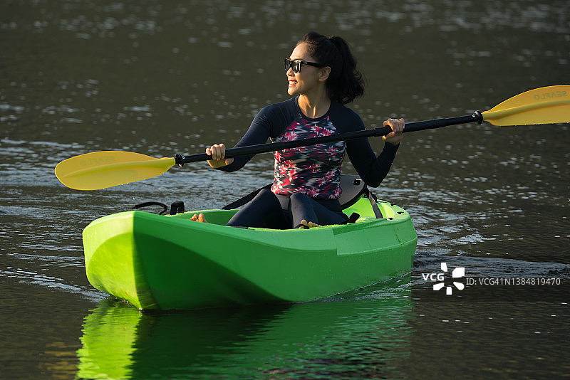 健康的亚洲女游客在泰国国家公园的湖上划皮划艇图片素材