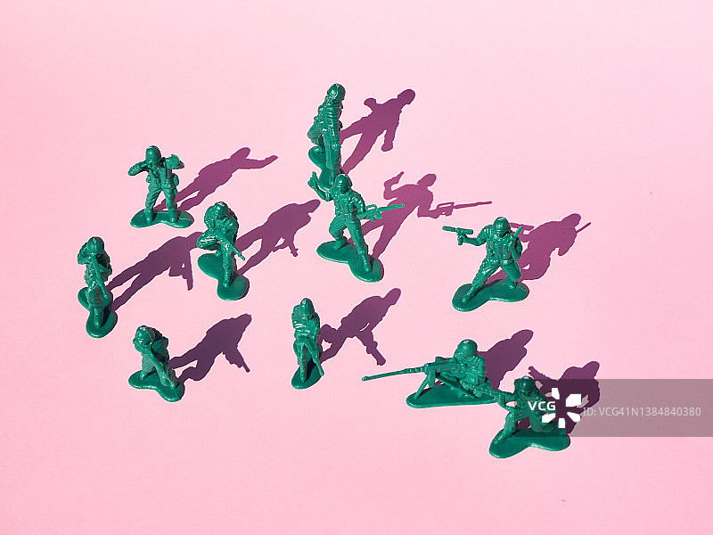 彩色背景上互相用枪指着的塑料玩具士兵图片素材