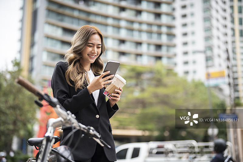 美丽的亚洲女商人看手机，非常高兴图片素材