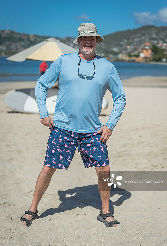 男人在墨西哥海滩上微笑，双手叉腰图片素材