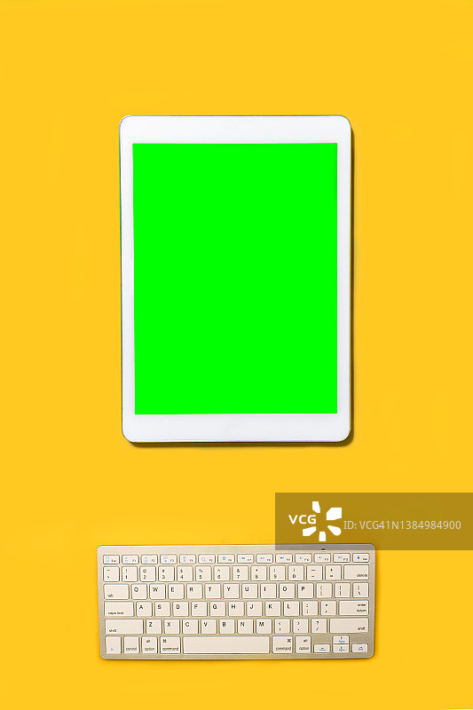 黄色背景上的无线键盘和数位板图片素材