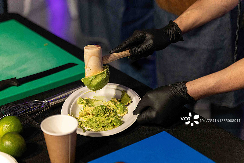 墨西哥厨师用锤子捣碎牛油果制鳄梨酱图片素材