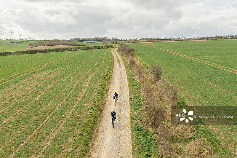 英国乡村砾石路上两名骑自行车者的无人机视角图片素材