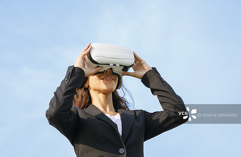 戴着VR眼镜，利用无线技术进行商务工作的女商人图片素材