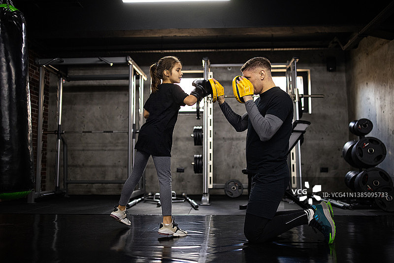 白人小女孩在健身俱乐部与男教练一起练习跆拳道图片素材