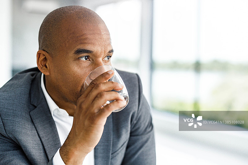 沉思的黑人男商人在办公室喝水图片素材