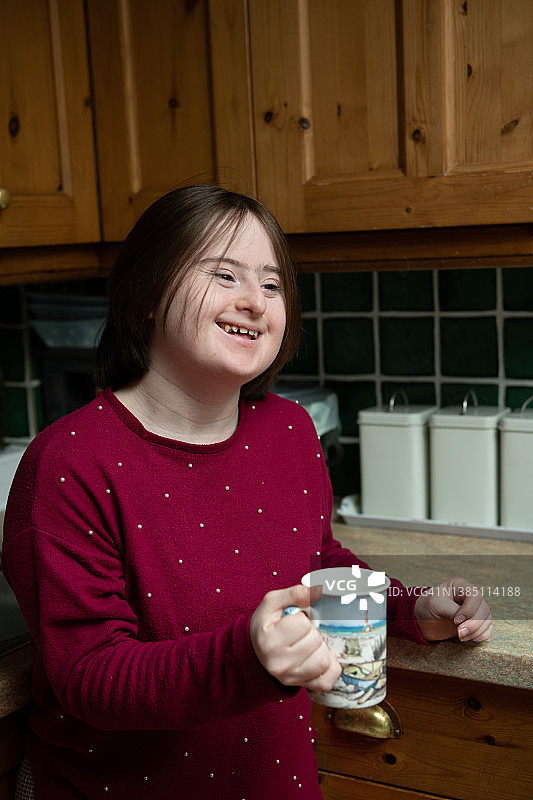 在自家厨房喝咖啡的唐氏综合征少女图片素材