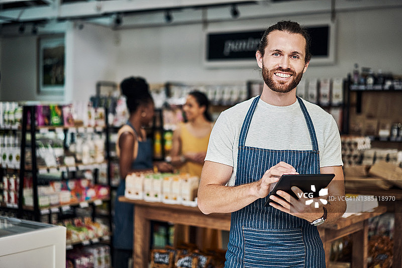 年轻男子在有机商店使用平板电脑工作图片素材