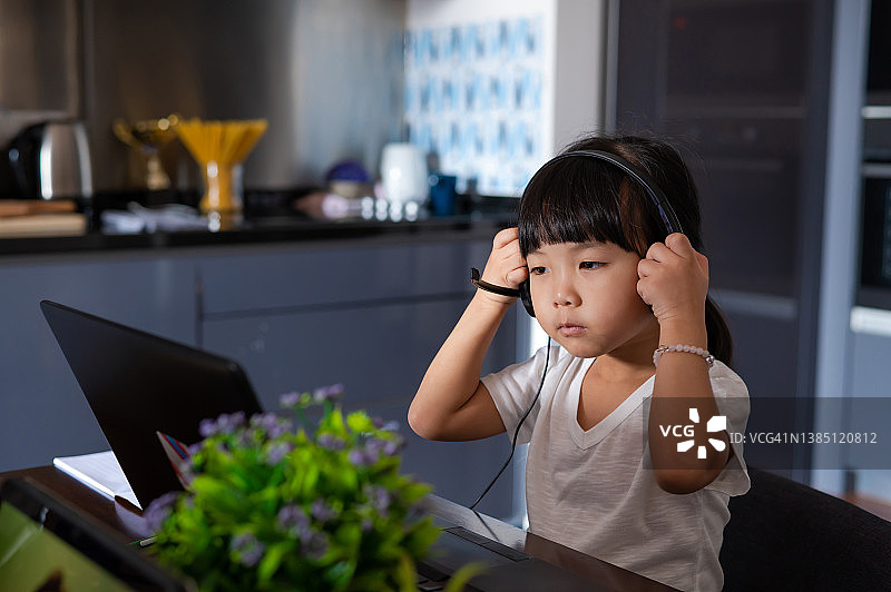 年轻的亚洲小学生准备在家用笔记本电脑与学校老师和同学进行视频会议图片素材