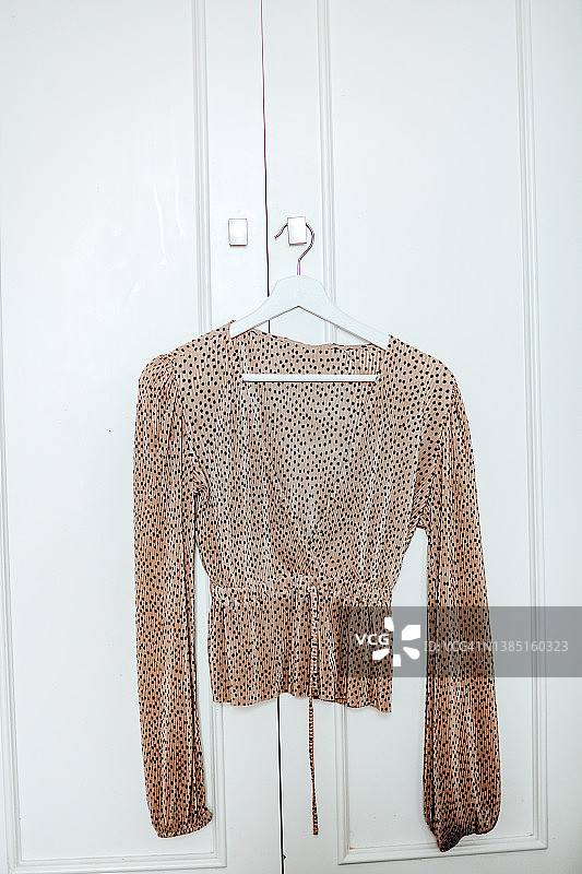 挂在白色墙壁上的棕色圆点女式衬衫图片素材