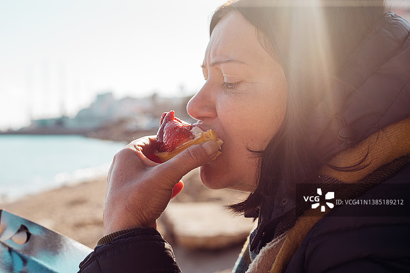 女人在户外吃草莓蛋糕图片素材