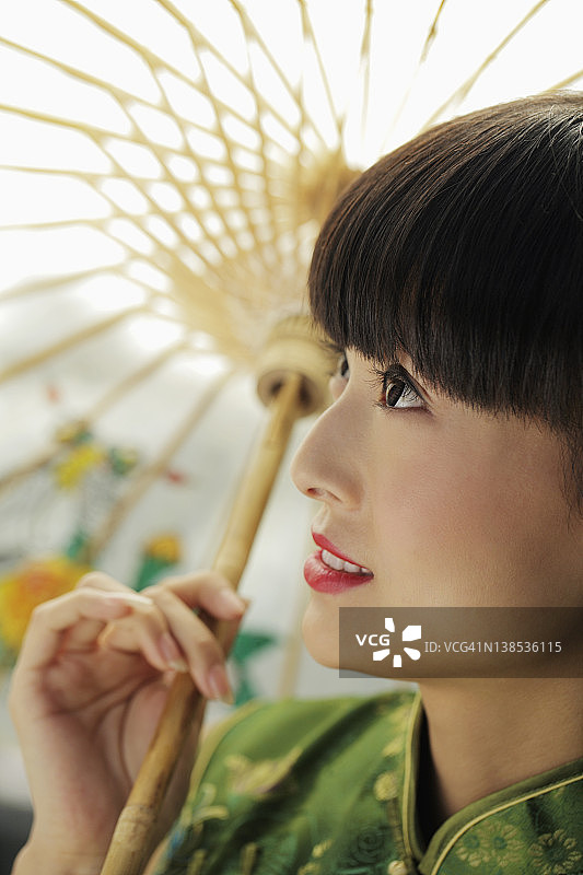 抬头撑伞的年轻女子侧面照图片素材