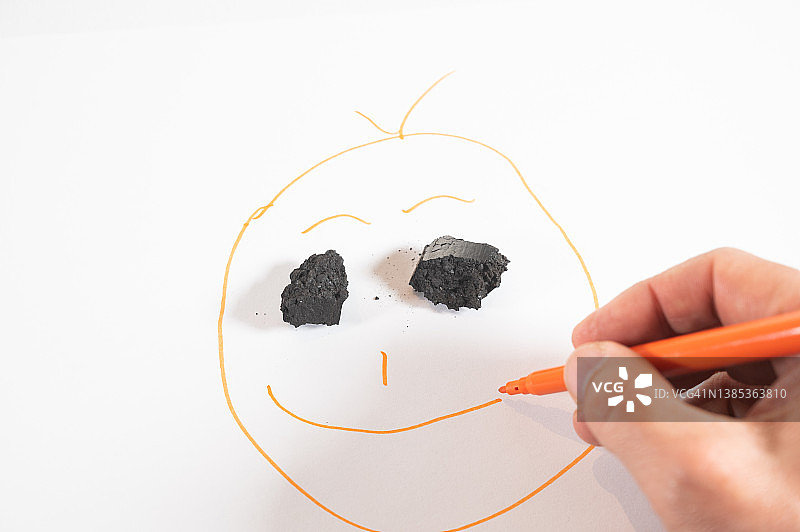 一个人用煤块画脸，完成了眼睛图片素材