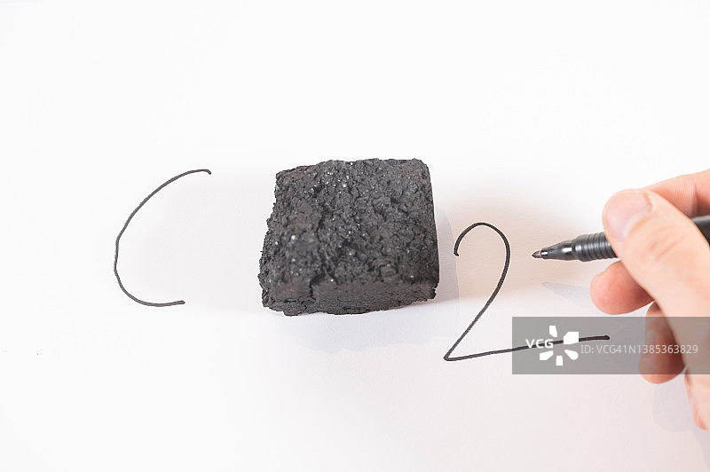 一个人在纸上写CO2。中心有一块煤图片素材