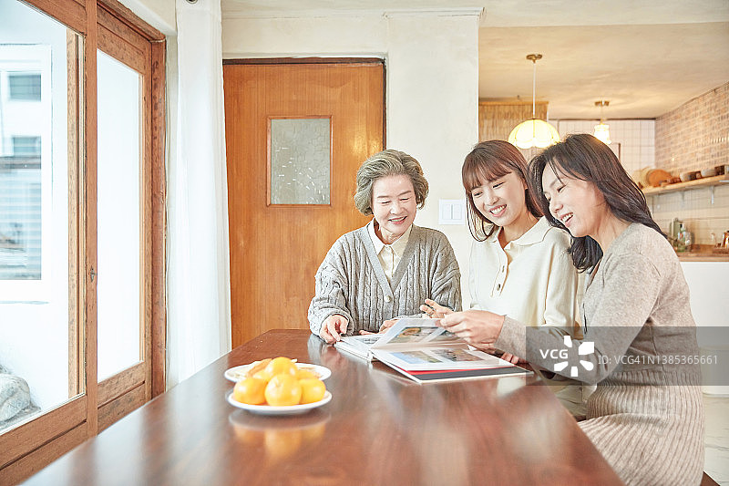 祖母、母亲和孙女一边看照片一边聊天图片素材