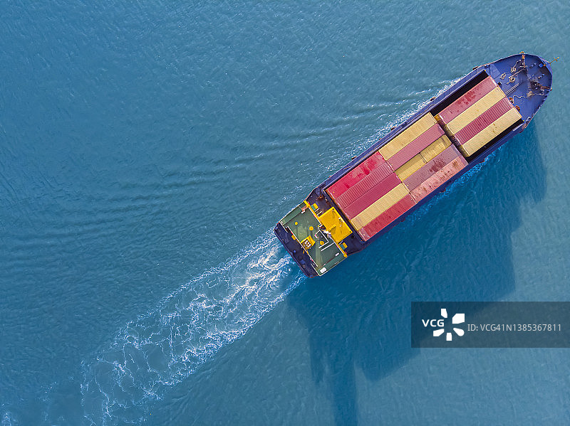 蓝色河流中航行的集装箱船航拍顶视图，关于集装箱船进出口运输业务。图片素材
