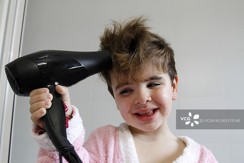 儿童用吹风机吹头发图片素材