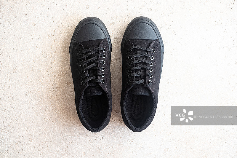 浅色混凝土背景上的通用黑色运动鞋，顶视图图片素材