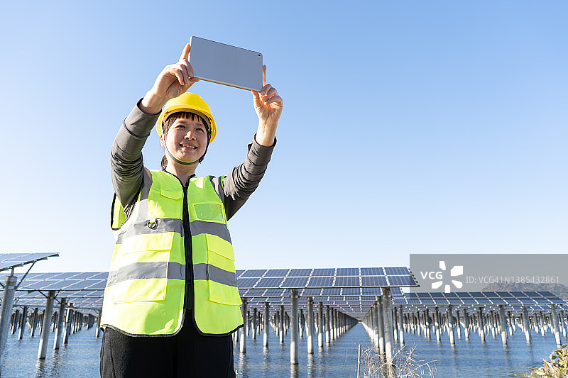 女工程师在太阳能发电厂用平板电脑拍照仰视角度图片素材