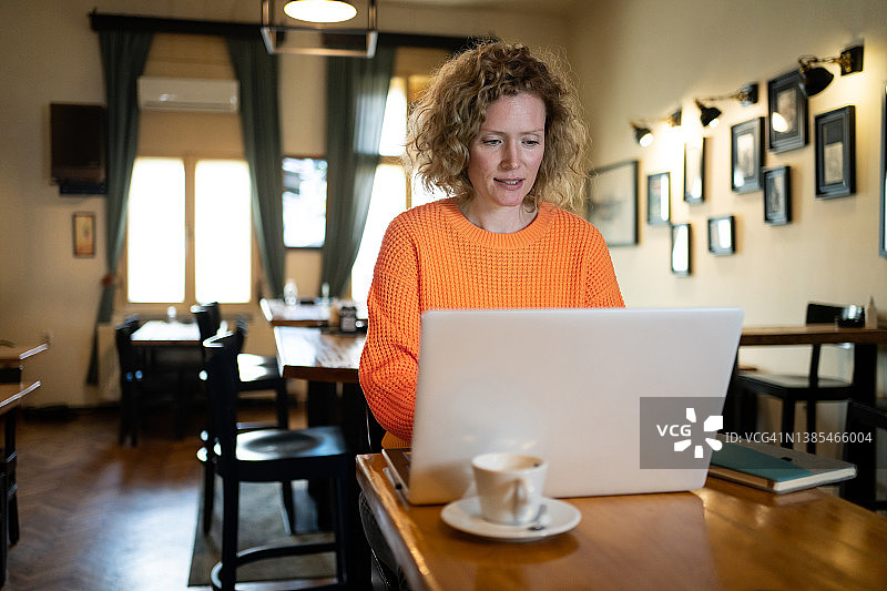 在现代咖啡店用笔记本电脑工作的白人女企业家图片素材
