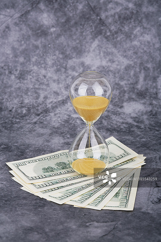 混凝土背景上的沙漏与美元图片素材