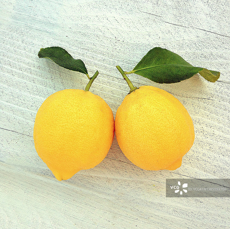 白色木板上的两个柠檬和叶子图片素材