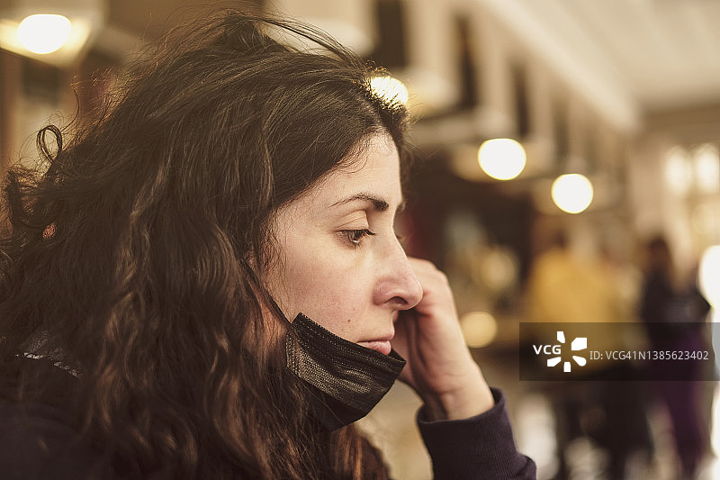 酒吧里因疫情疲惫不堪、口罩戴错位的女人图片素材