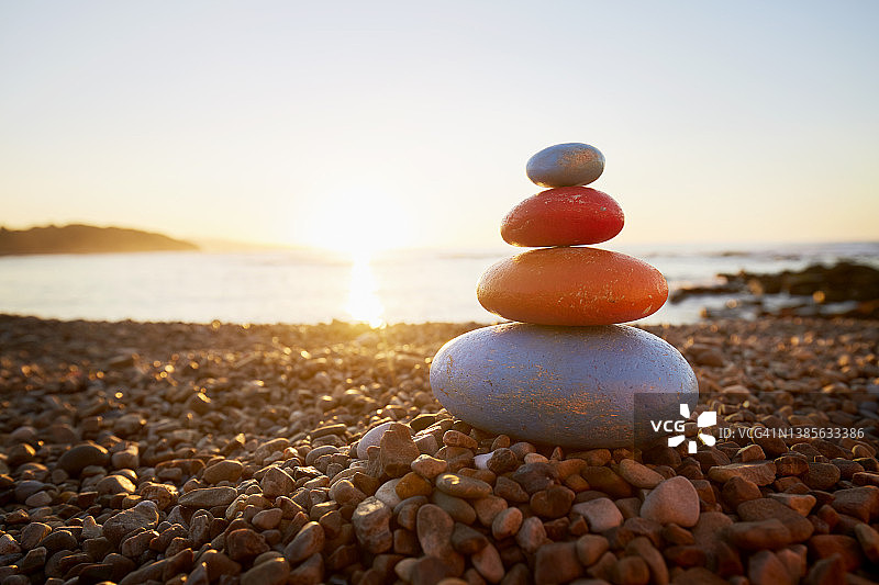 日落时分海边的彩色平衡石堆图片素材