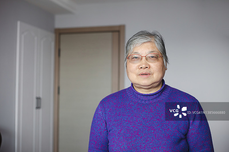 年长的东亚妇女在客厅看向镜头微笑图片素材