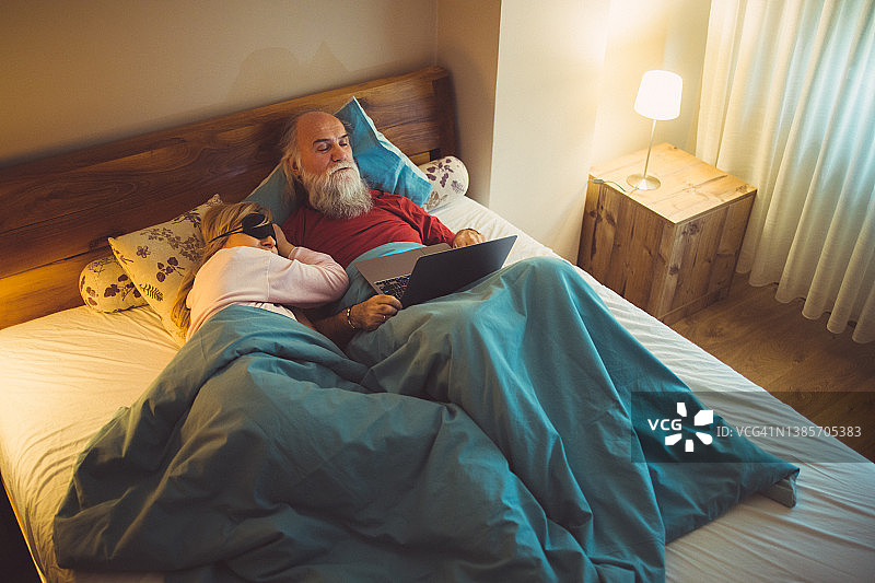 老年夫妇在床上通过网络看电视图片素材