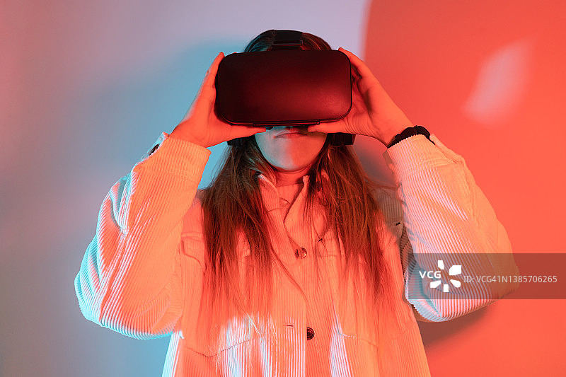戴VR头显在未来灯光背景中娱乐的女人图片素材