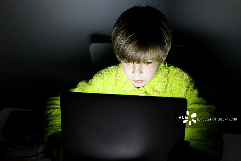 男孩晚上在家使用笔记本电脑图片素材