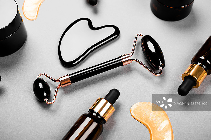 面部按摩器：黑色玛瑙面部滚轮、面霜罐和精华液瓶、抗衰老刮痧按摩、护肤和彩妆化妆品图片素材