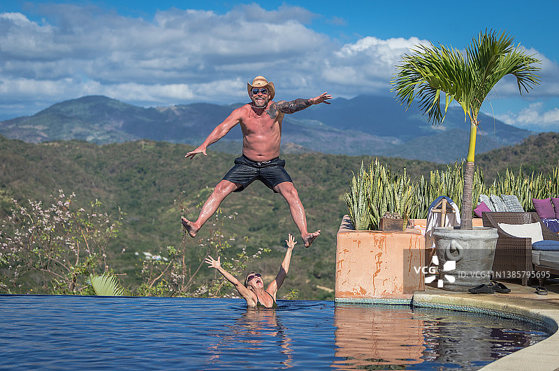 中年男子跳入泳池，女子欲接图片素材