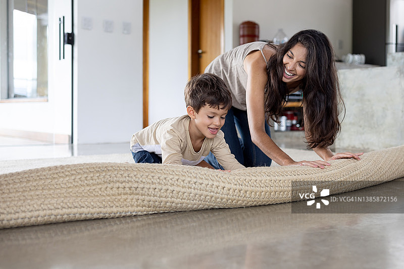 男孩在家帮妈妈展开地毯图片素材