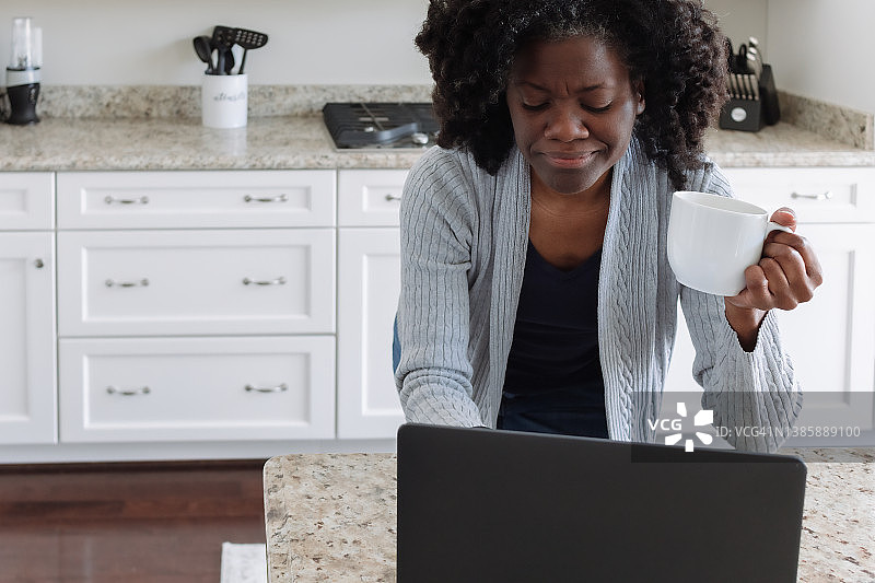 在厨房用笔记本电脑工作的女人图片素材