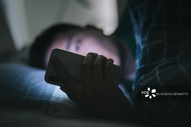在床上使用智能手机的男人图片素材