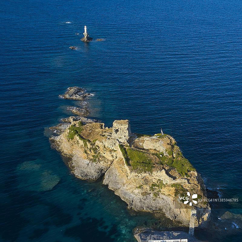 无人机拍摄,岩石岛上的堡垒,岩石上的灯塔,柔和的晚霞,大海清澈,海蓝和绿松石,安德罗斯镇,乔拉,安德罗斯岛,基克拉迪斯,希腊图片素材