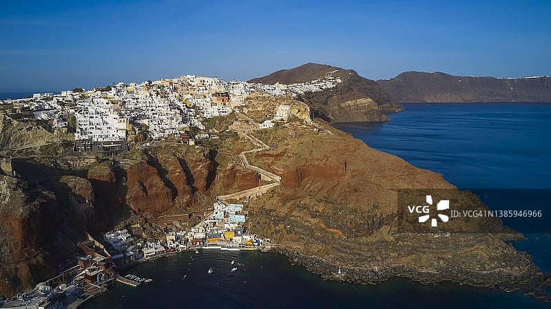 无人机拍摄：从海上高空拍摄，圣托里尼岛伊亚的Ammoudi港口和山坡上的房屋图片素材