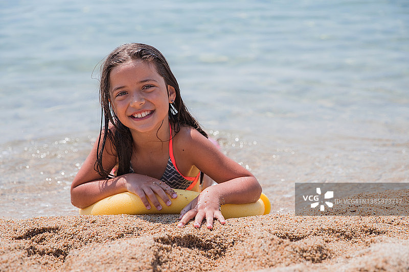 儿童躺在沙滩上的游泳浮条上图片素材