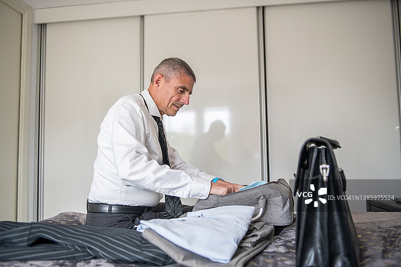 旅行打包行李：商务男士在酒店打包图片素材