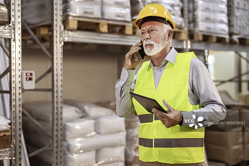 男年长主管在仓库用手机通话图片素材
