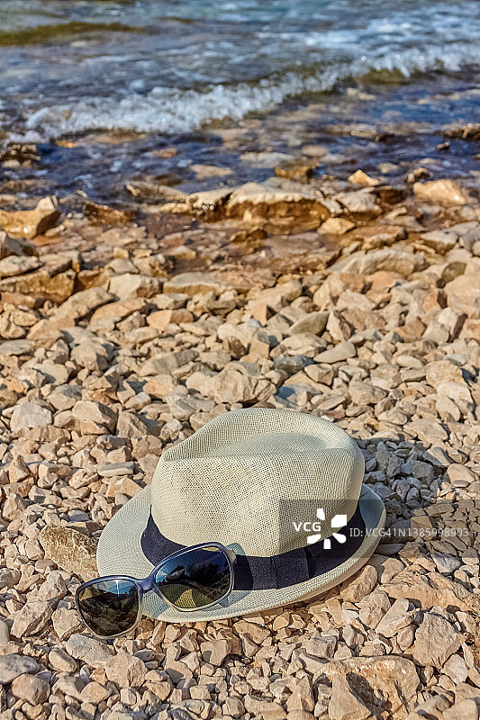 躺在鹅卵石海滩上的帽子和太阳镜图片素材