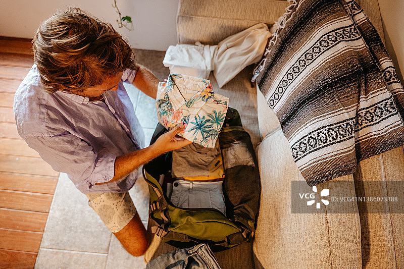 男旅行者打包行李将衣服放入行李袋图片素材