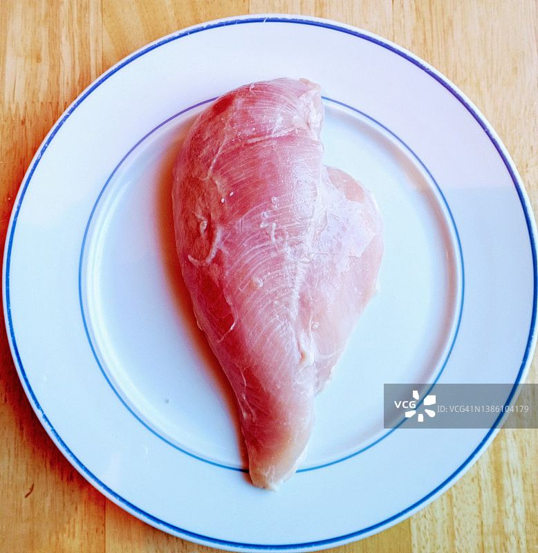 盘子上正在解冻的冷冻鸡胸肉图片素材