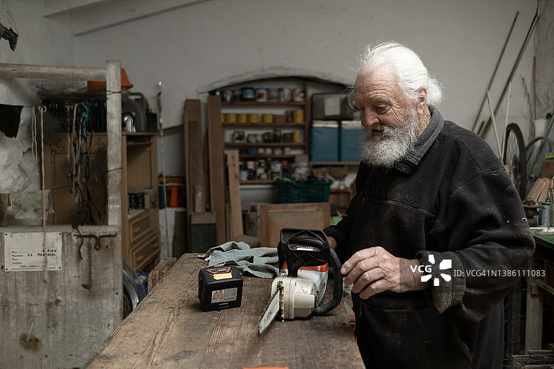 老年男人在家准备用于园艺的电锯图片素材