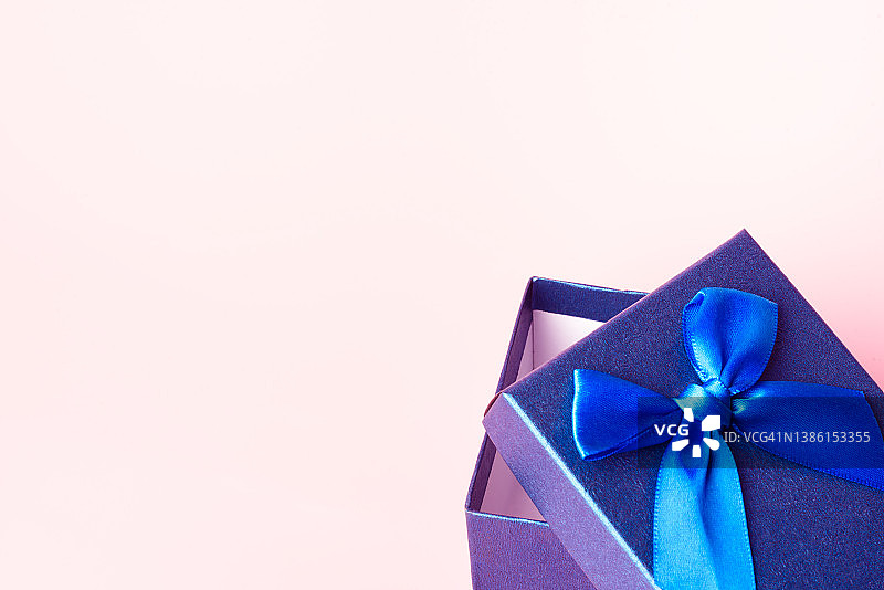 粉色背景上的蓝色礼品盒正面照：简约圣诞新年概念图片素材
