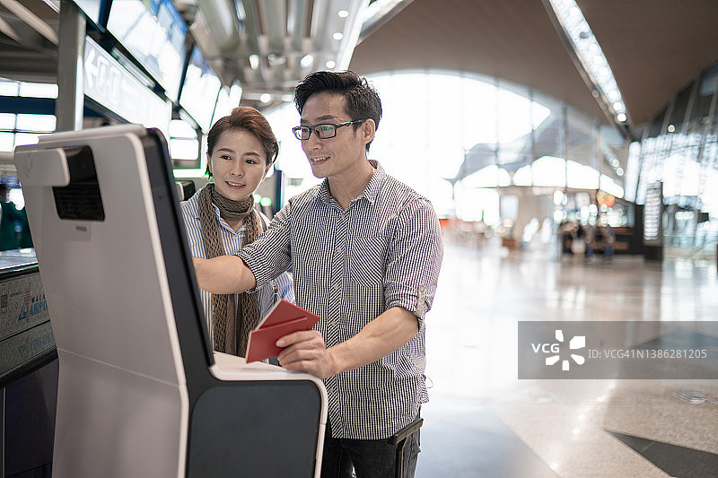 在中国机场通过自助值机办理登机的中国籍亚洲夫妇图片素材